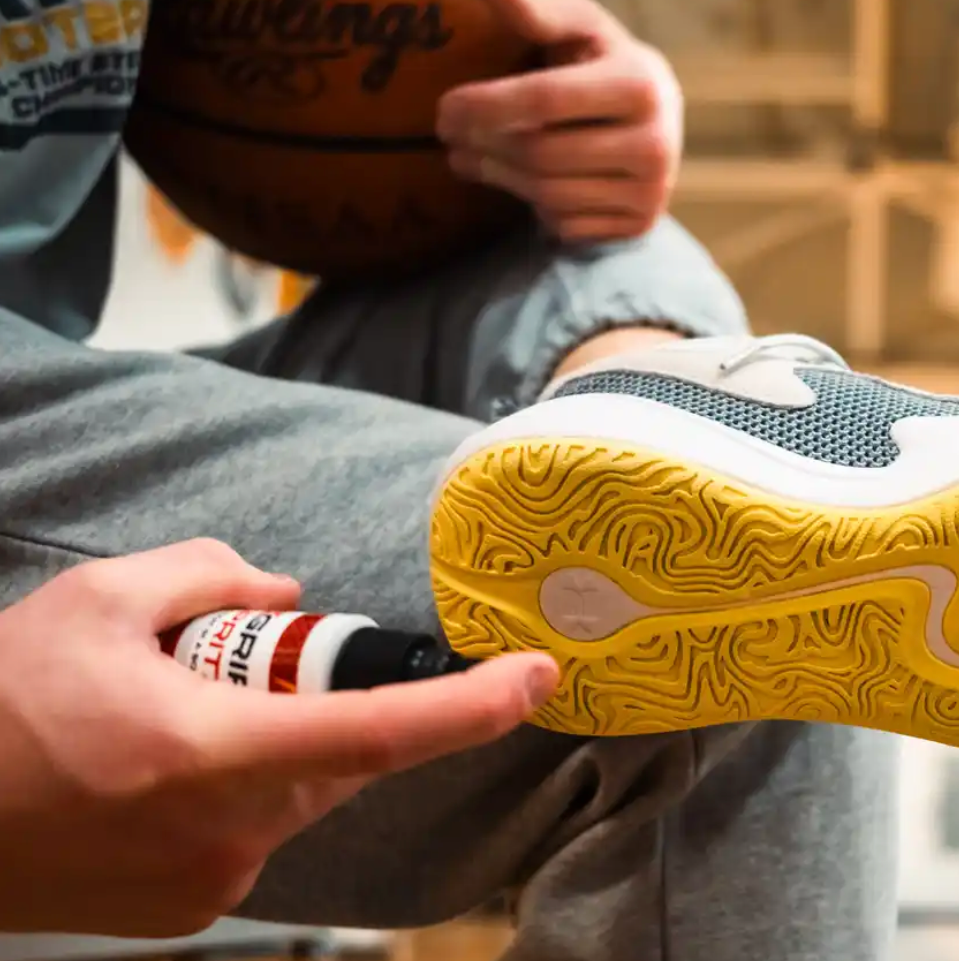 Grip Spritz Basketball Shoe Grip Spray being applied to shoe sole courtside in a high school gym